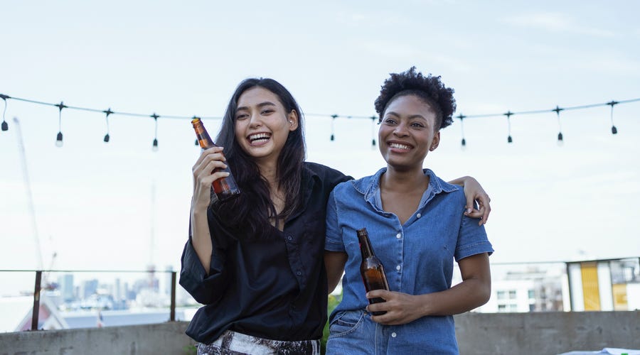 Two friends having a chat on a rooftop party