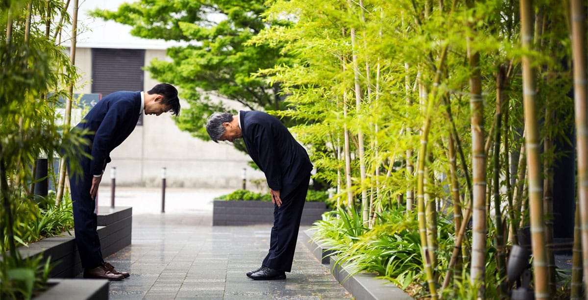 Two Japanese businessmen bowing to each other as a greeting