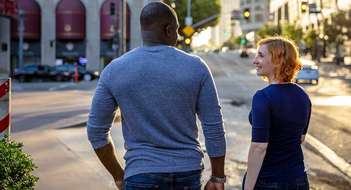 Man and woman crossing a street in the USA and talking to each other