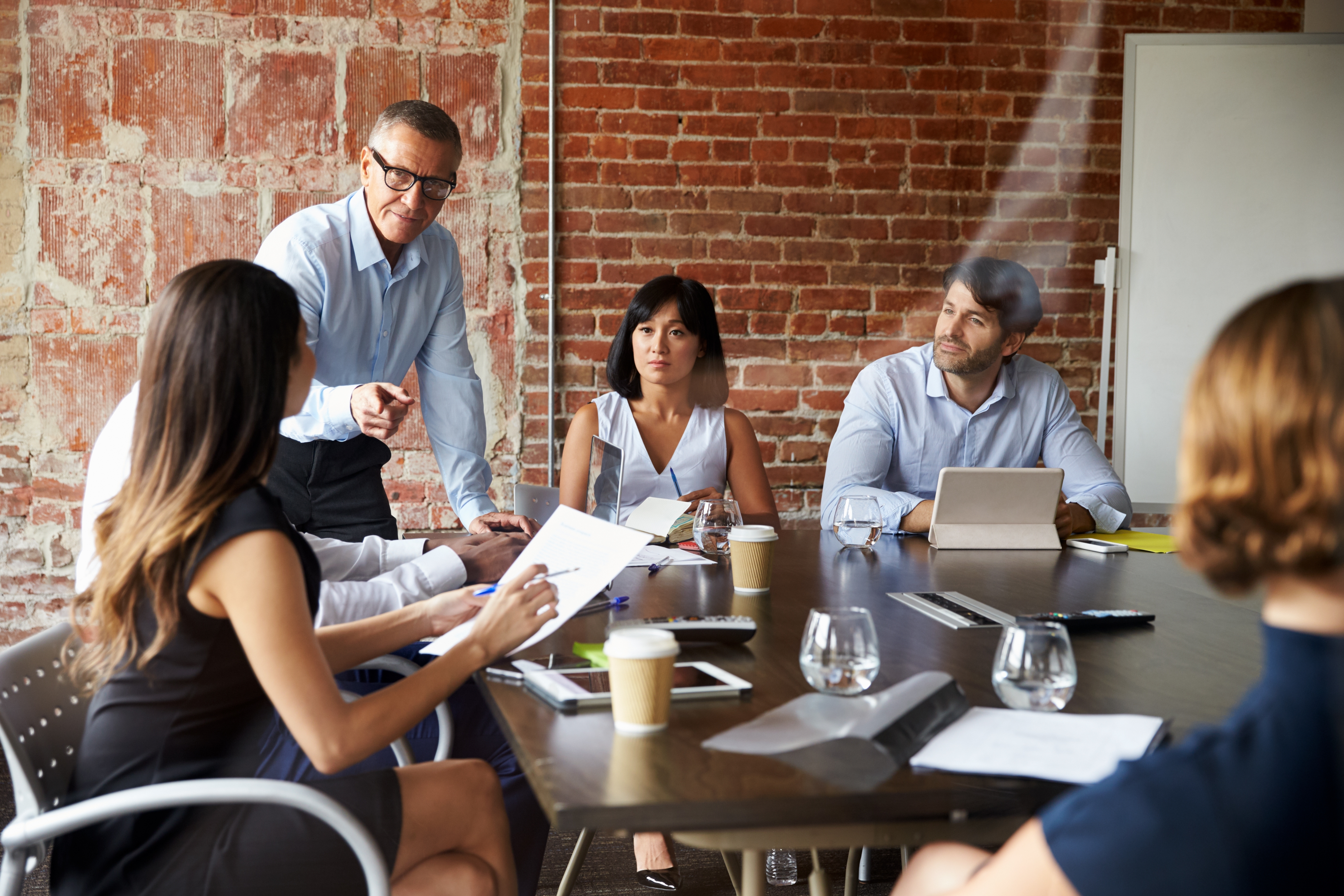 Group of professionals sitting at a table and listening to their language instructor during business language learning