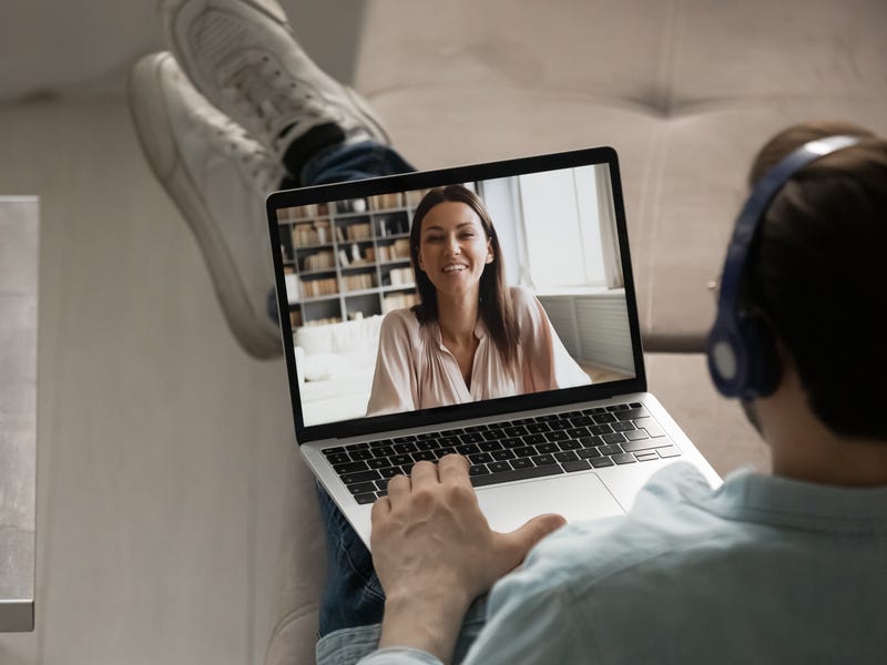 Man with a headphone attending an online language class from his laptop
