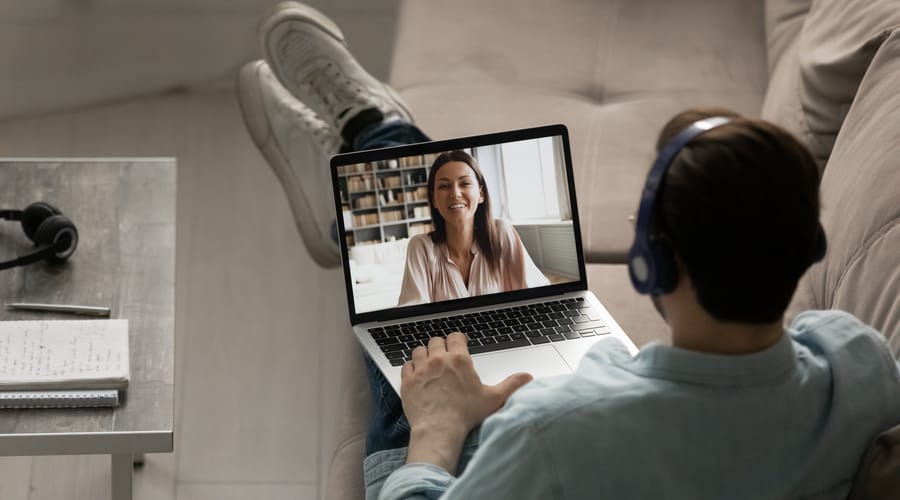 Man with a headphone attending an online language class from his laptop
