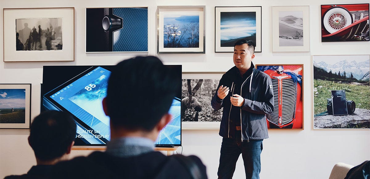 Man in an art gallery talking to his coworkers