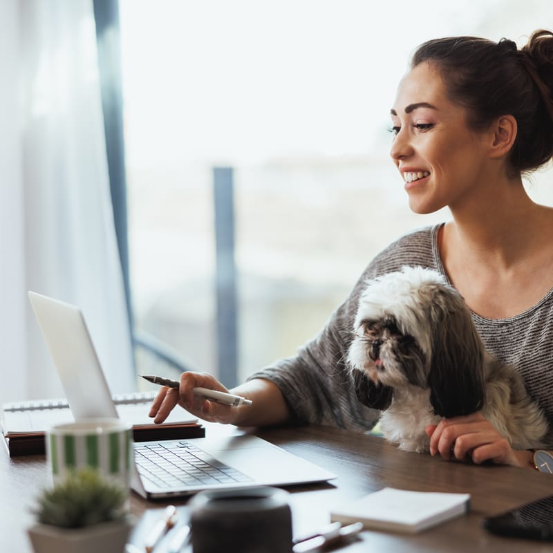 Woman sitting on the couch with her laptop and practicing her speaking skills with Berlitz's AI-assisted learning tool