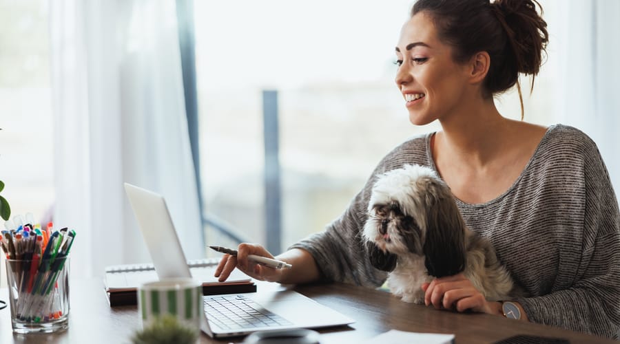 Woman sitting on the couch with her laptop and practicing her speaking skills with Berlitz's AI-assisted learning tool