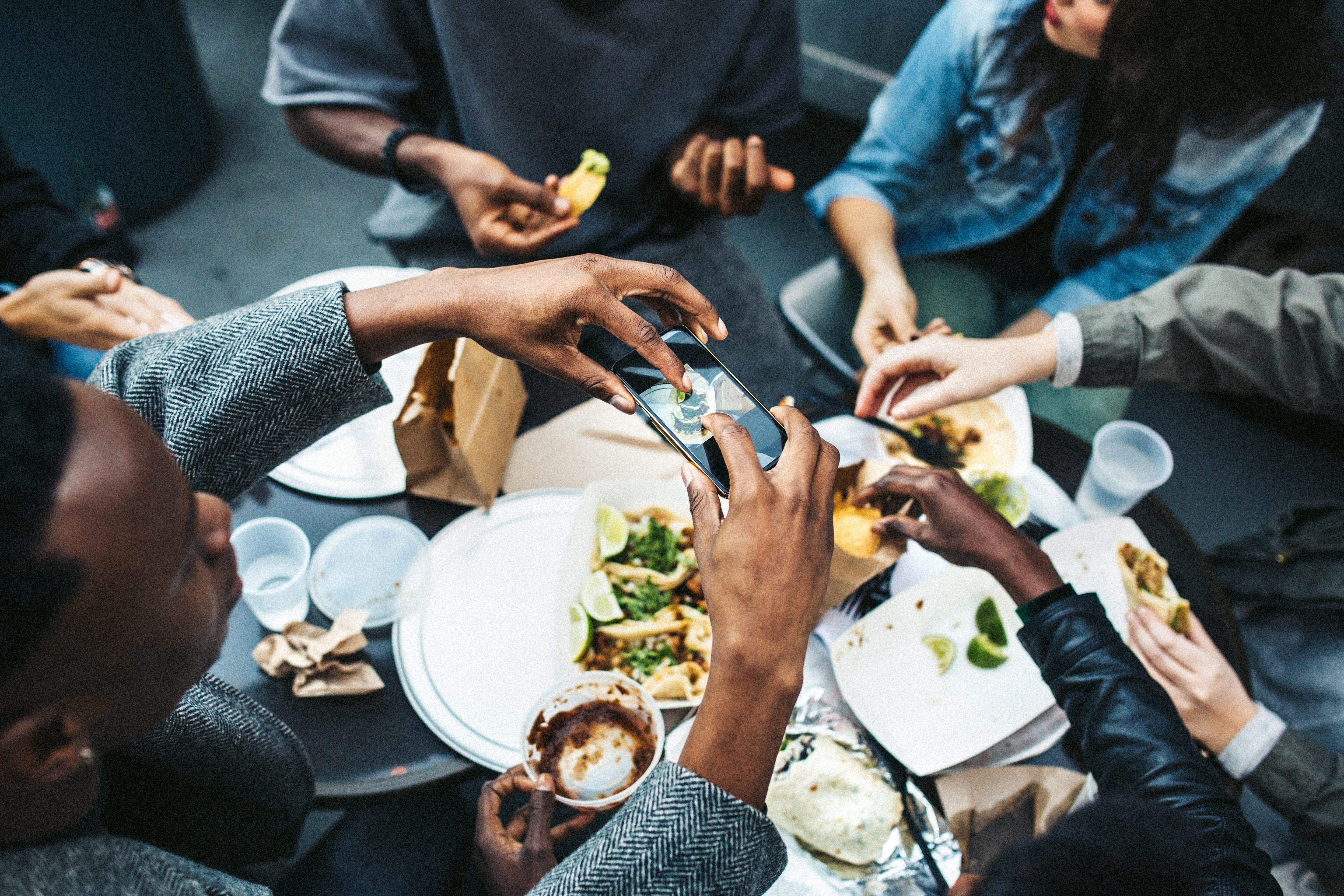 Group of friends sitting around a table of traditional American food and eating together