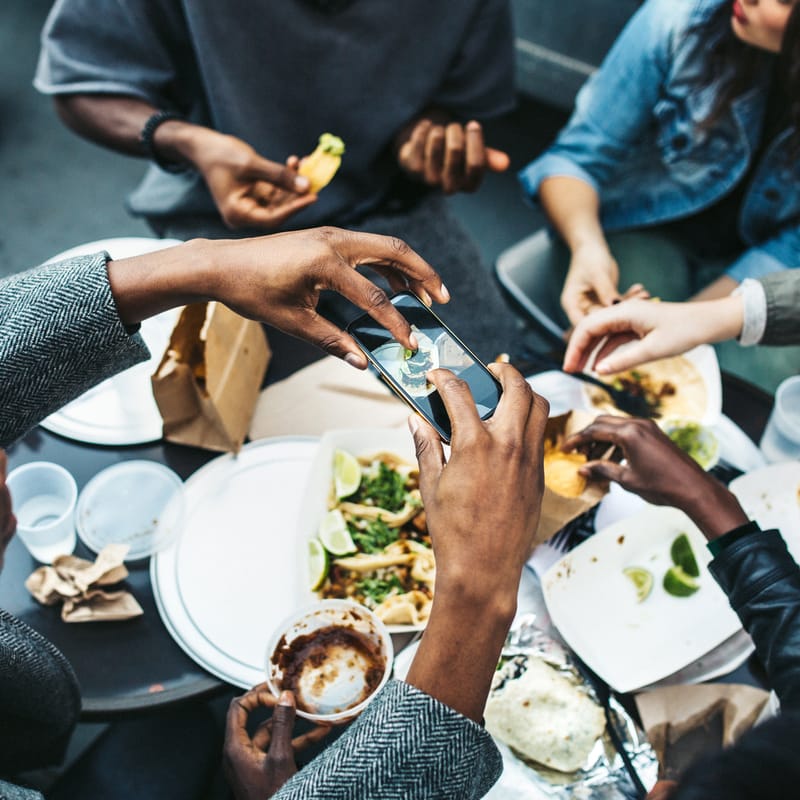 Group of friends sitting around a table of traditional American food and eating together