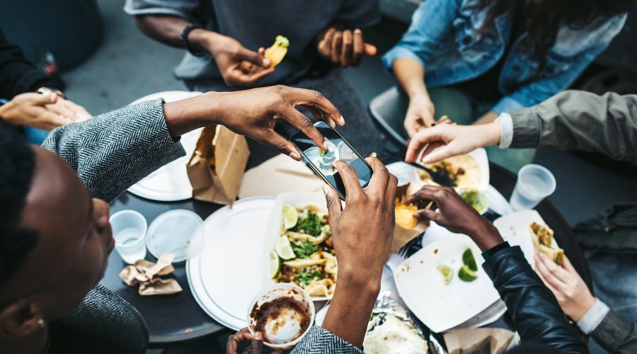 Group of friends sitting around a table of traditional American food and eating together