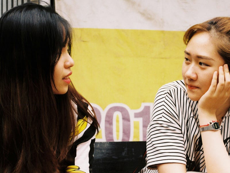 Two friends sitting next to each other and saying sorry for a mistake in Spanish