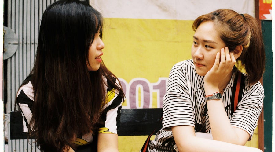 Two friends sitting next to each other and saying sorry for a mistake in Spanish