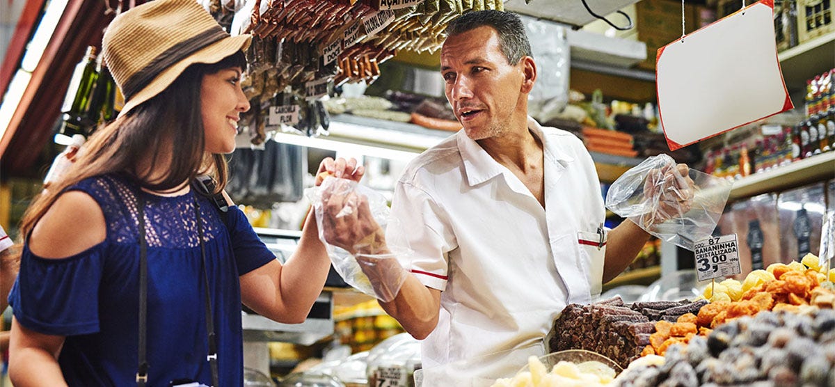 Woman in a market talking to a merchant in Spanish