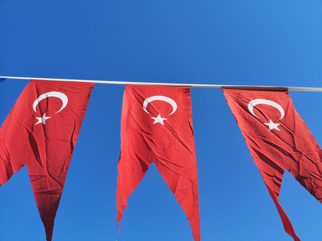 Three Turkish flags against the blue sky