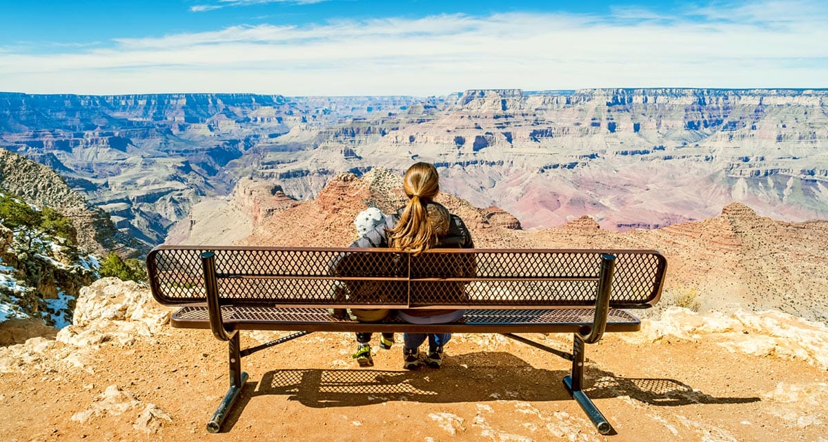 Woman sitting on a bench and looking at the Grand Canyon in Arizona USA