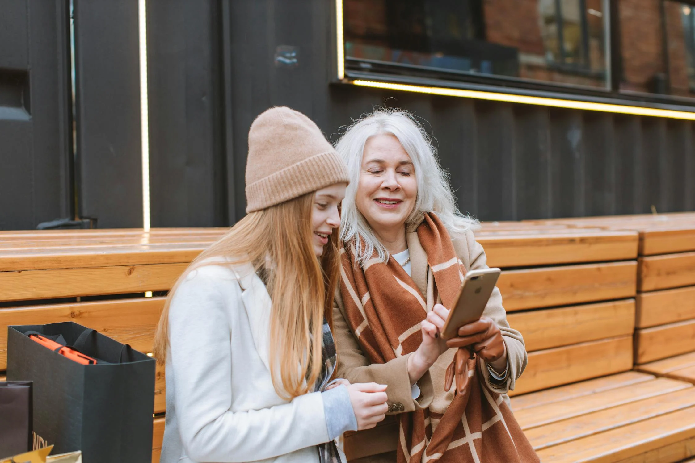 Woman and her mom looking at a phone outside and talking about the present perfect tense in English