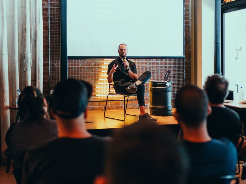 Man sitting in a chair and talking to his audience