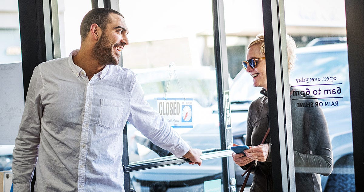 Man holding the door open for a woman