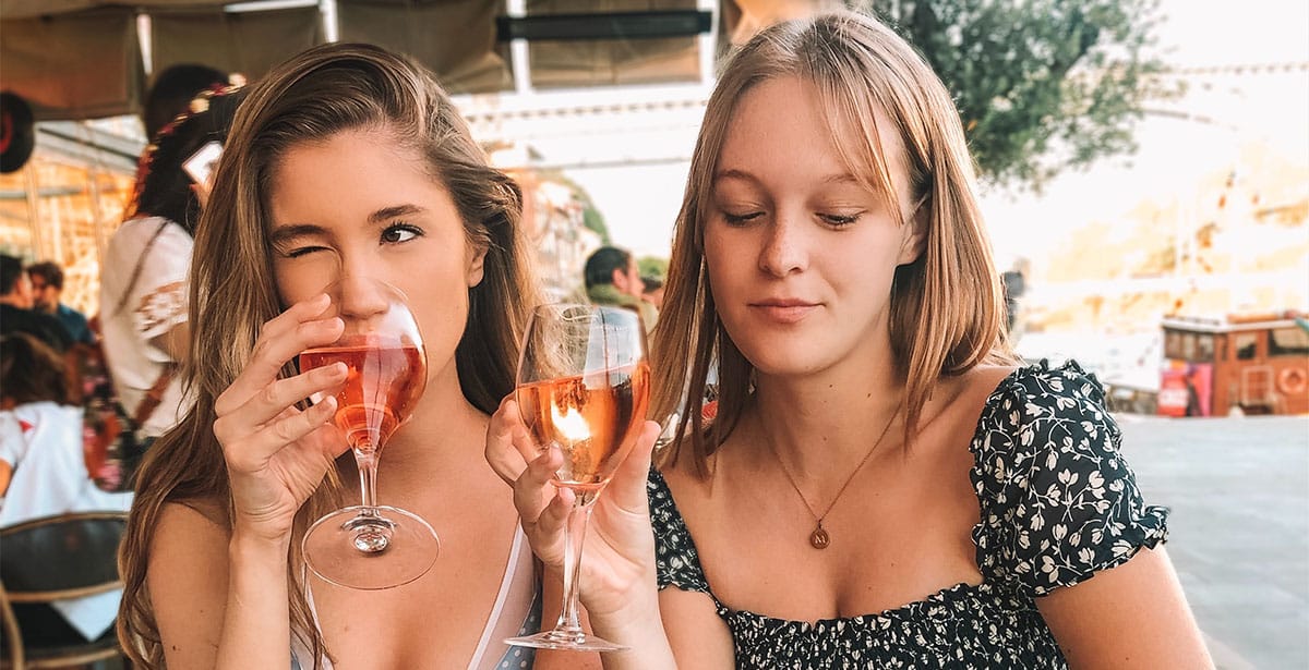 Girl sitting next to her friend and winking at someone at the other table