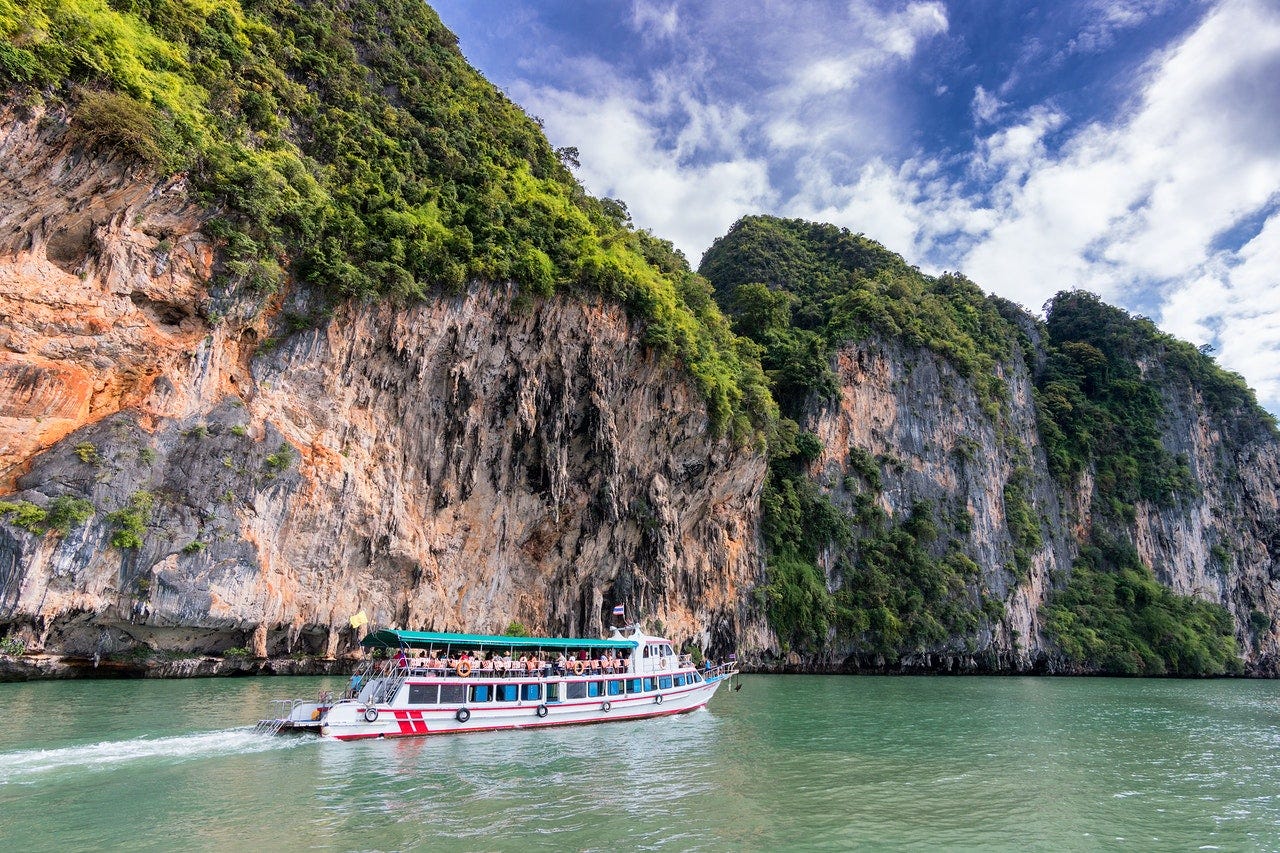 A boat with tourist in front of an island of Thailand