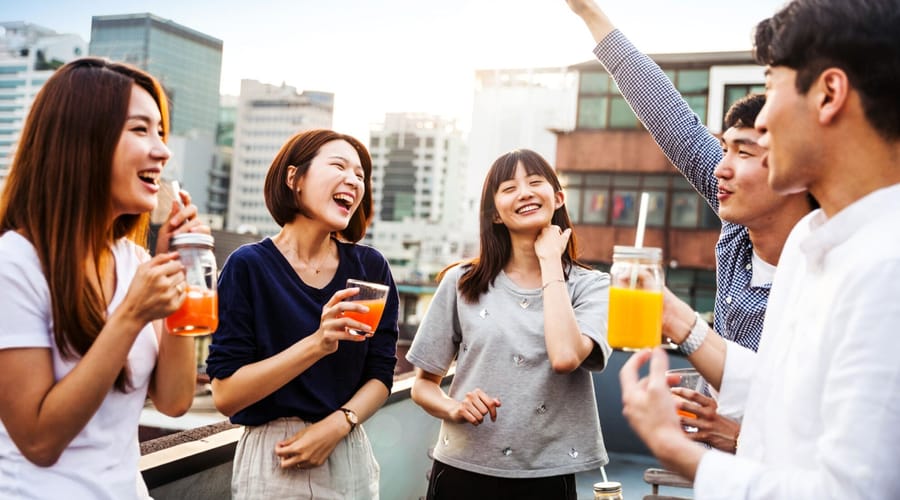 Friends on a rooftop smiling and laughing while celebrating with drinks in their hands
