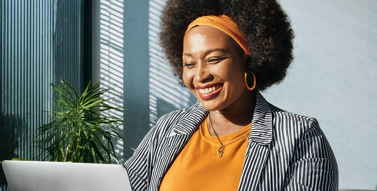 Woman smiling in front of a laptop after her class with Berlitz where she learned about the French grammar