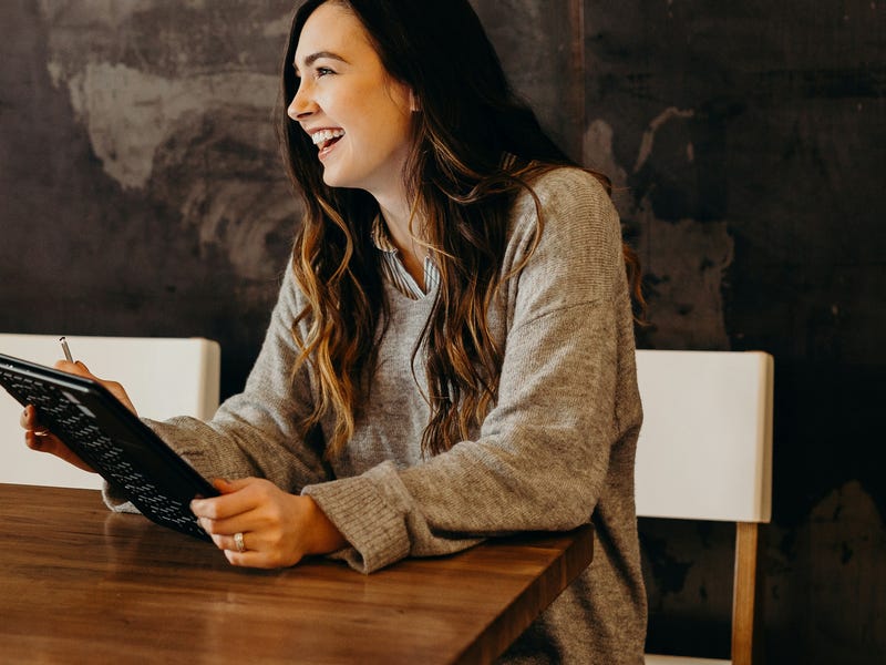 Woman in a restaurant laughing with her friend while using the past continuous tense
