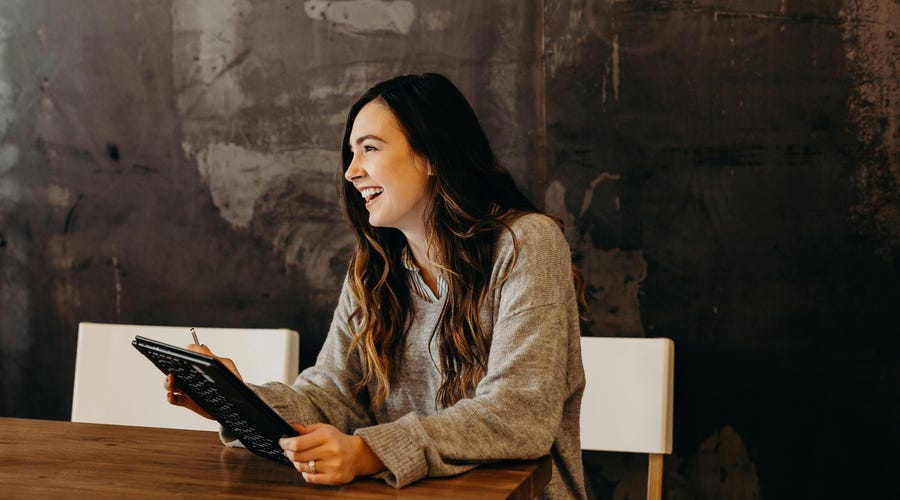 Woman in a restaurant laughing with her friend while using the past continuous tense