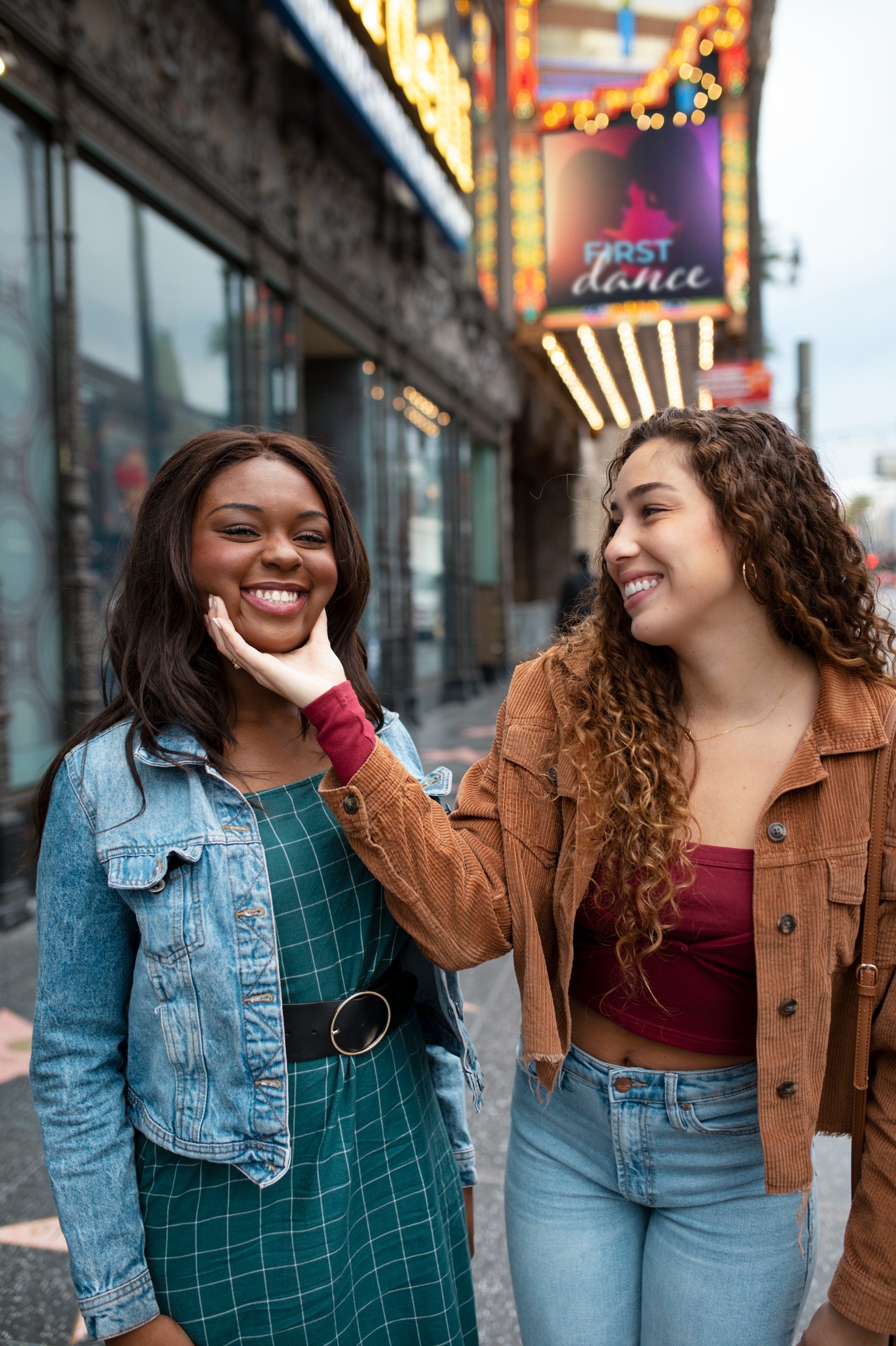 Woman holding the face of her friend who is speaking another language and laughing with her