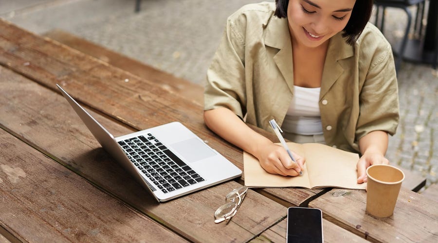 Woman in front of a laptop making notes while learning about French grammar rules