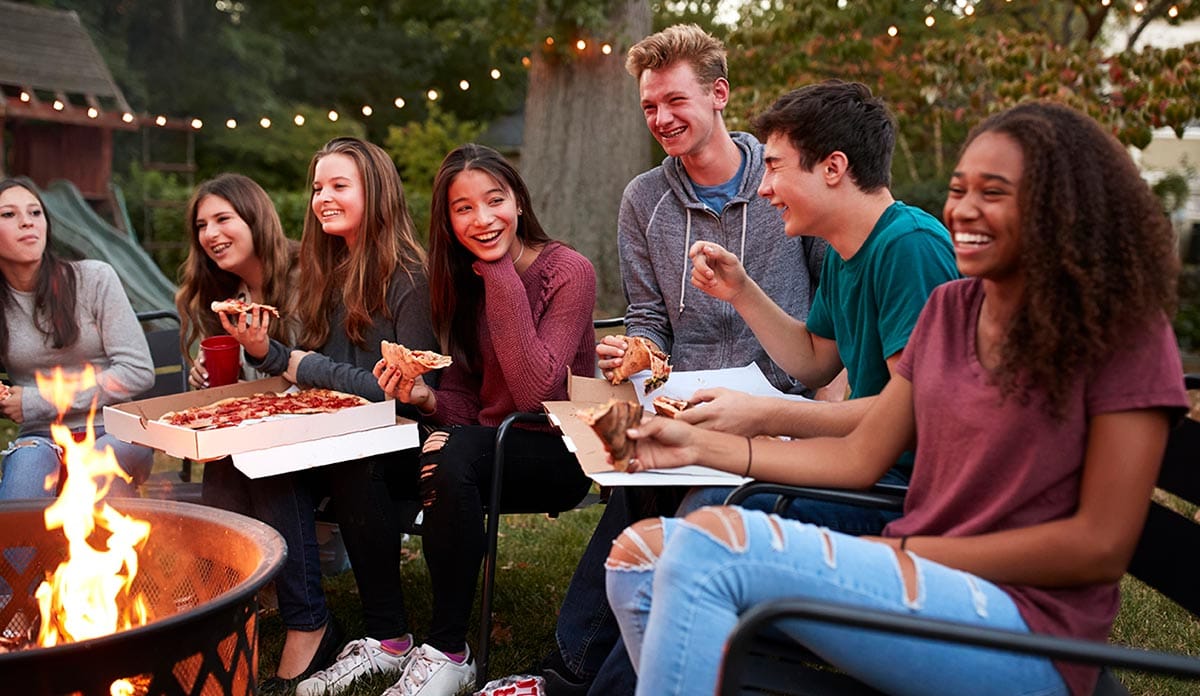 American teenagers during a garden party eating pizza together
