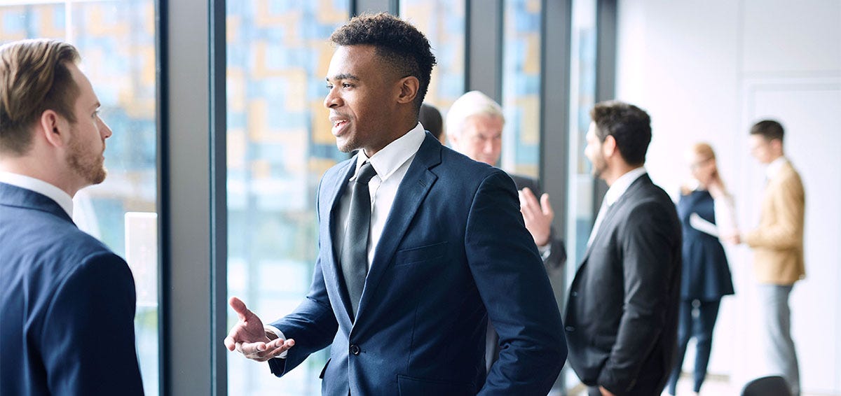 Business professional in a suit holding out his hand to shake hands with another professional