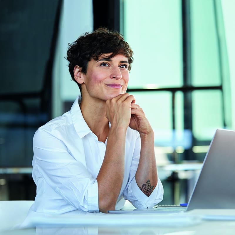 Woman sitting at her desk and smiling after her DEI training at her workplace
