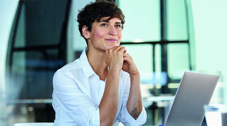 Woman sitting at her desk and smiling after her DEI training at her workplace