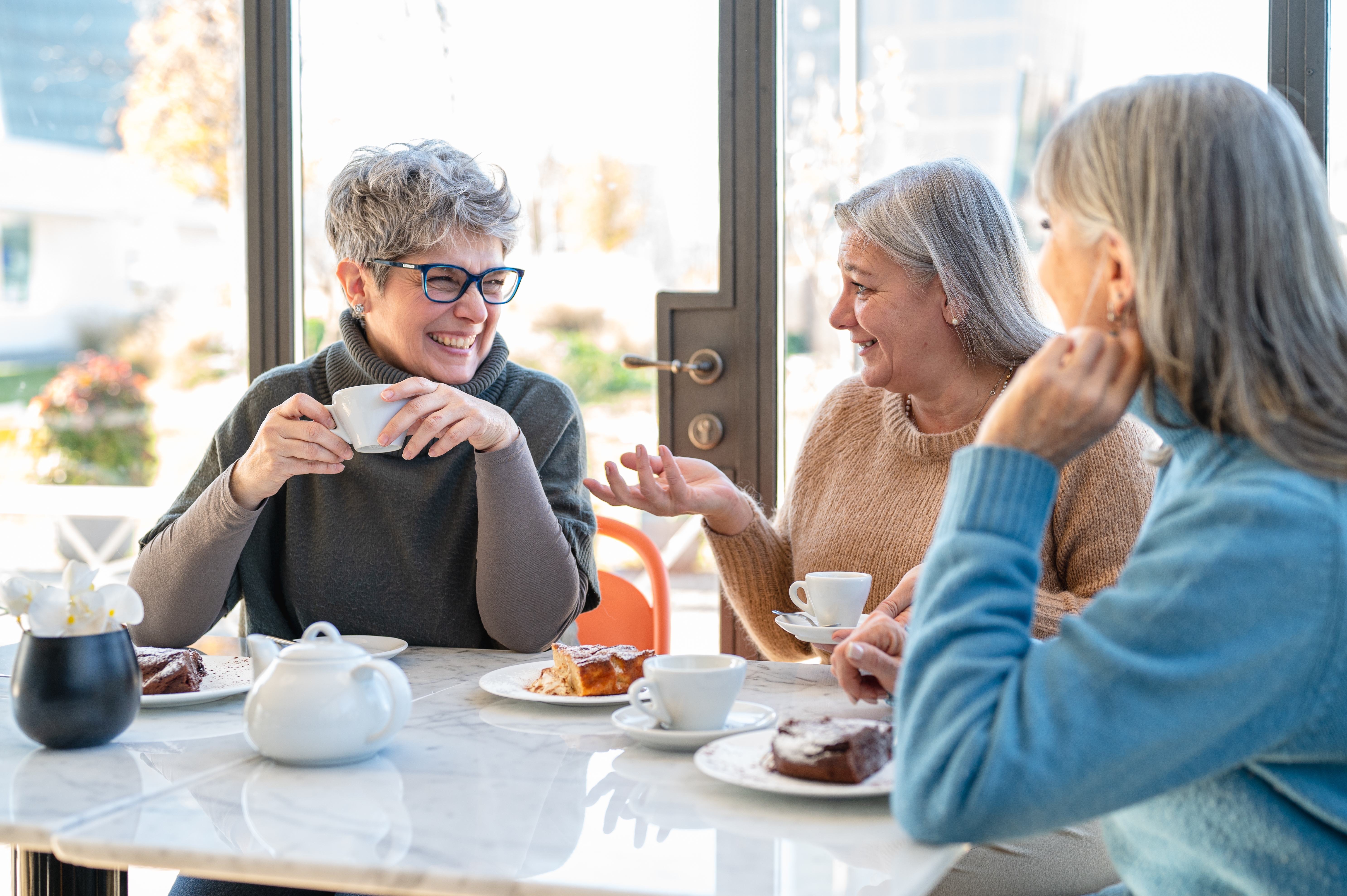 Older women chatting with each other in English while drinking coffe