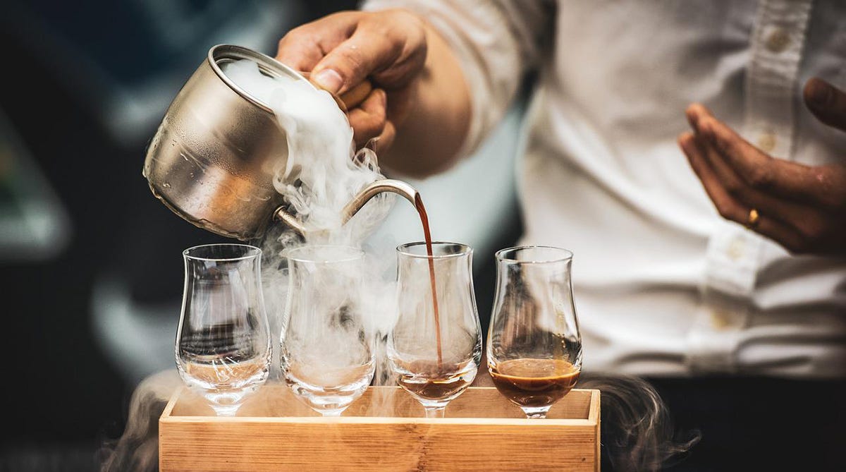 Barista pouring Turkish coffee in four glasses