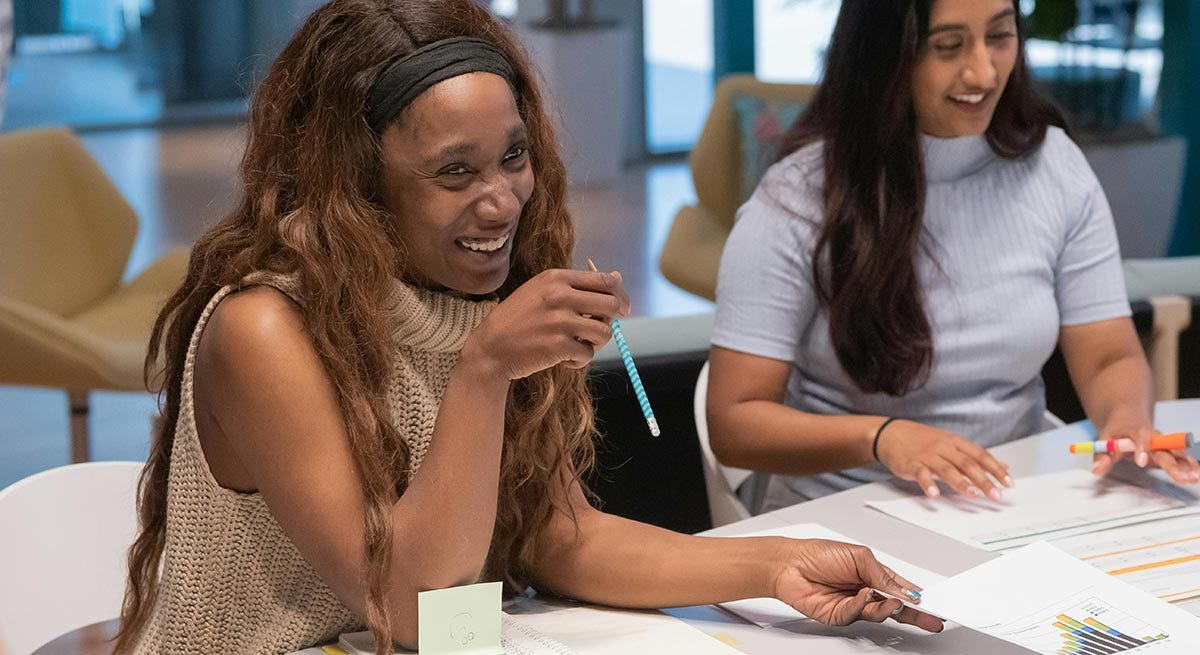 Women in their workplace making notes during a meeting and smiling