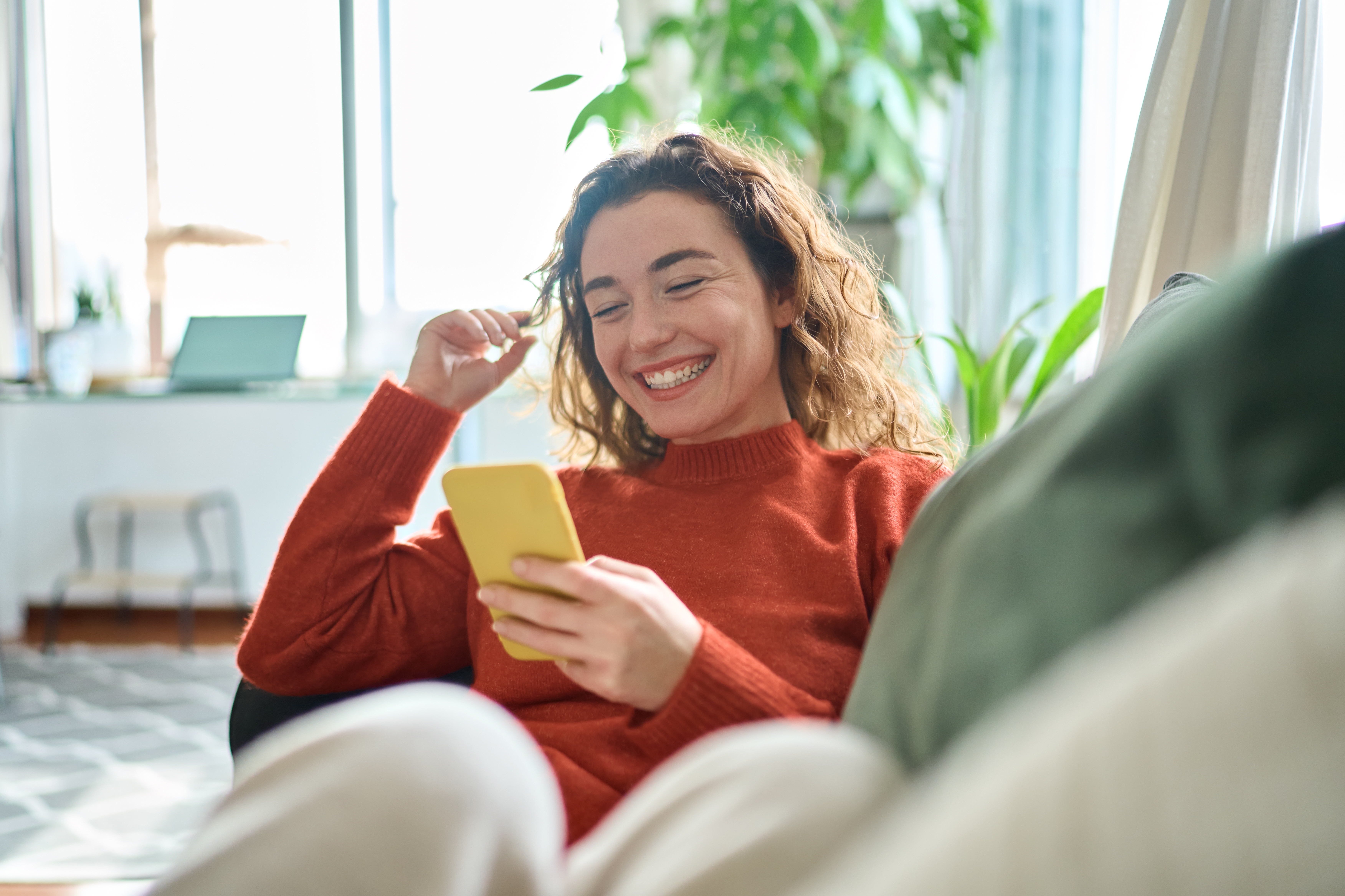 Woman smiling at her phone while learning Spanish online with Berlitz