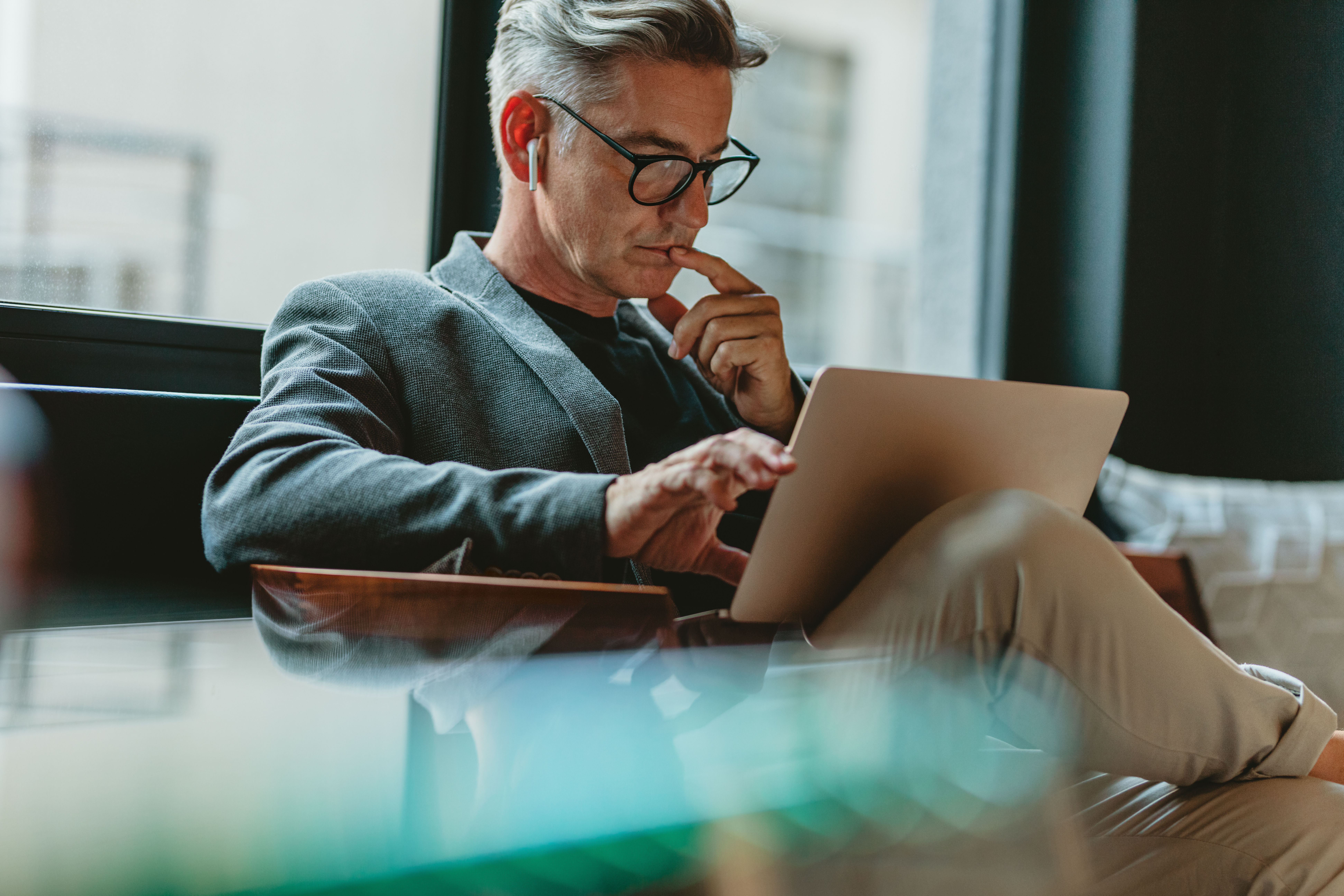 Businessman with a laptop in his lap learning a new language online with Berlitz