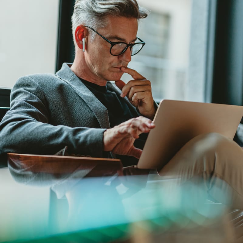 Businessman with a laptop in his lap learning a new language online with Berlitz