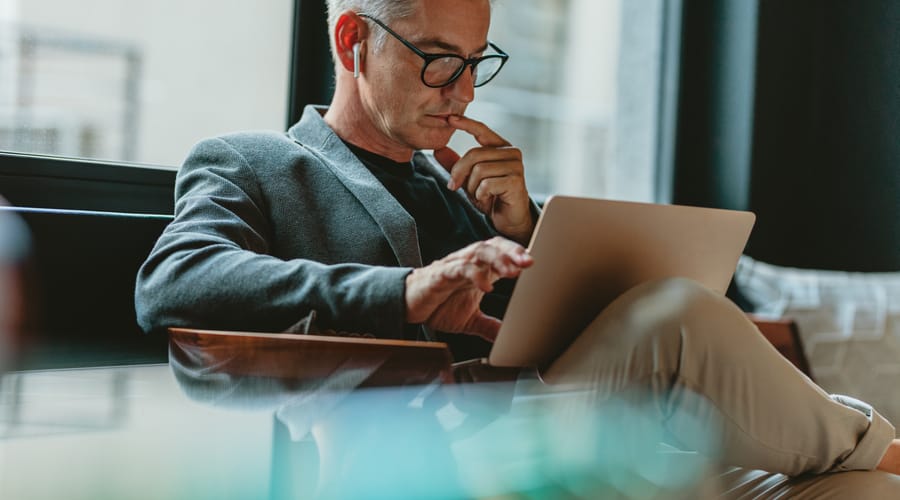 Businessman with a laptop in his lap learning a new language online with Berlitz