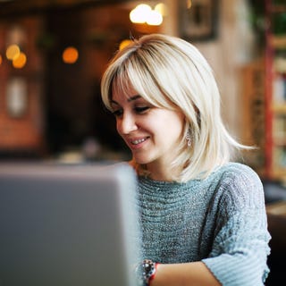 Woman taking an online French lesson with Berlitz UAE in a coffeeshop on her laptop