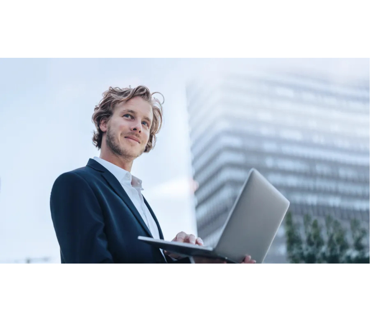 A well-dressed professional stands outdoors holding a laptop, with a modern office building in the background, suggesting work, technology, and a corporate setting.