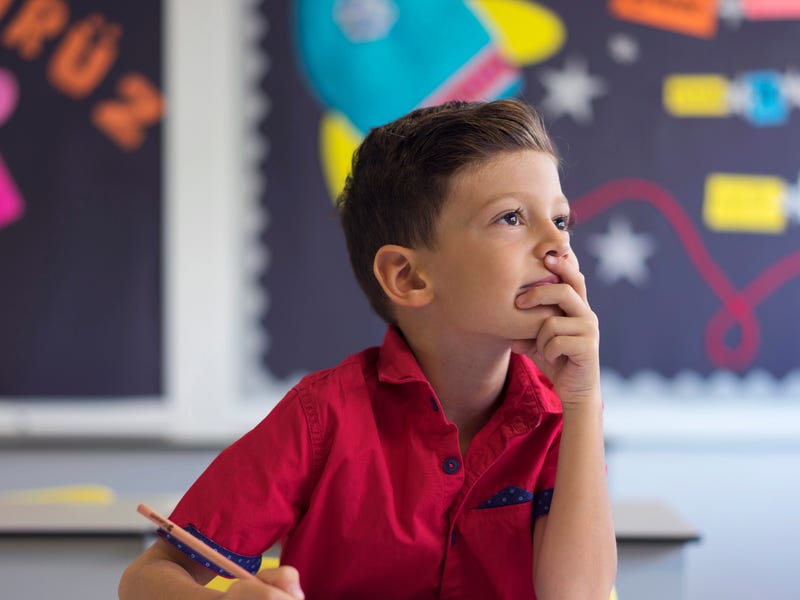 Little boy in school learning about German numbers and holding a pen