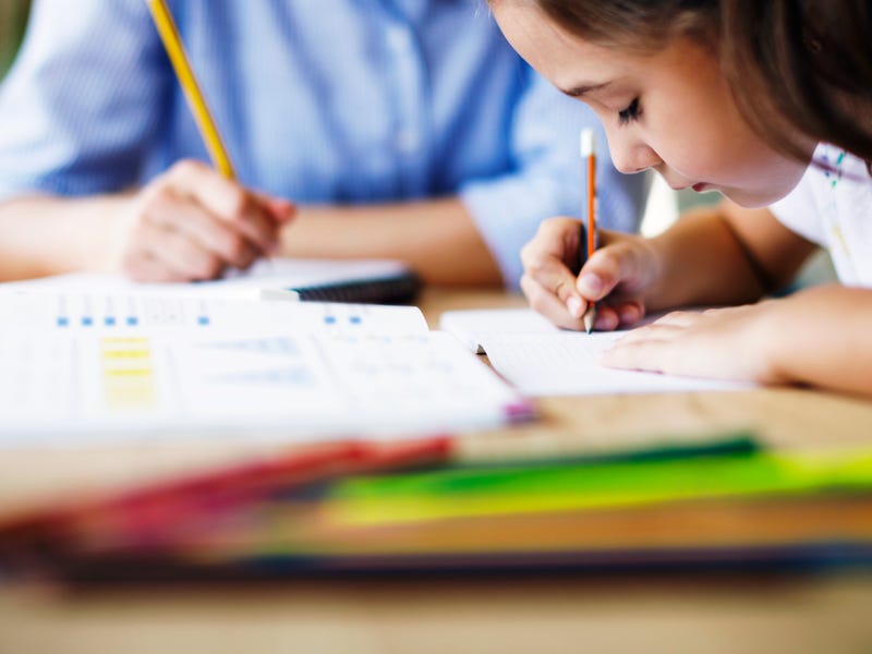 Little girl in the school learning about Spanish numbers and making notes with a pencil in her hand