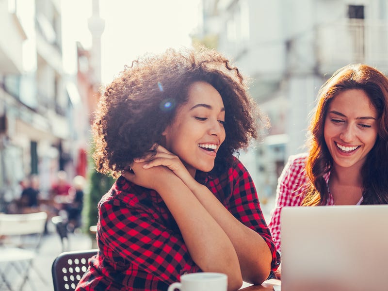 Two women in front of a laptop learning how to say goodbye  in Spanish