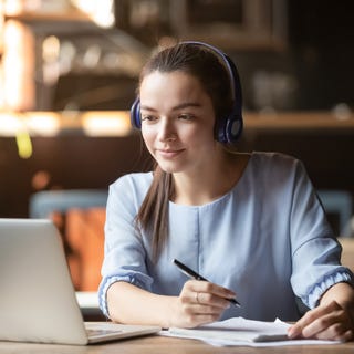 Woman with a headset making notes during her online Spanish class with Berlitz UAE