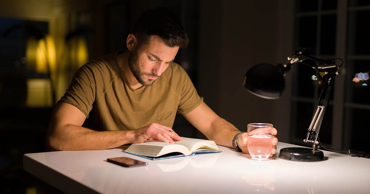 Mann sitzt am Tisch und liest ein Buch