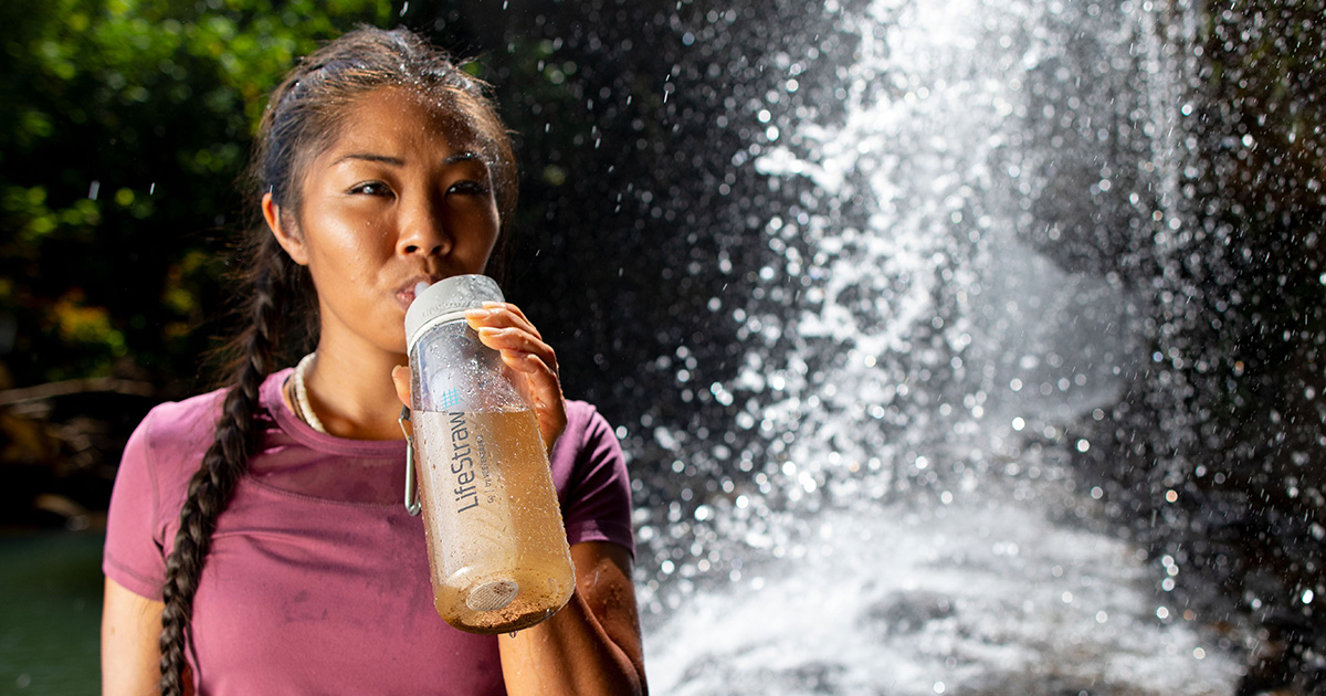 Une femme boit dans une bouteille filtrante de Lifestraw