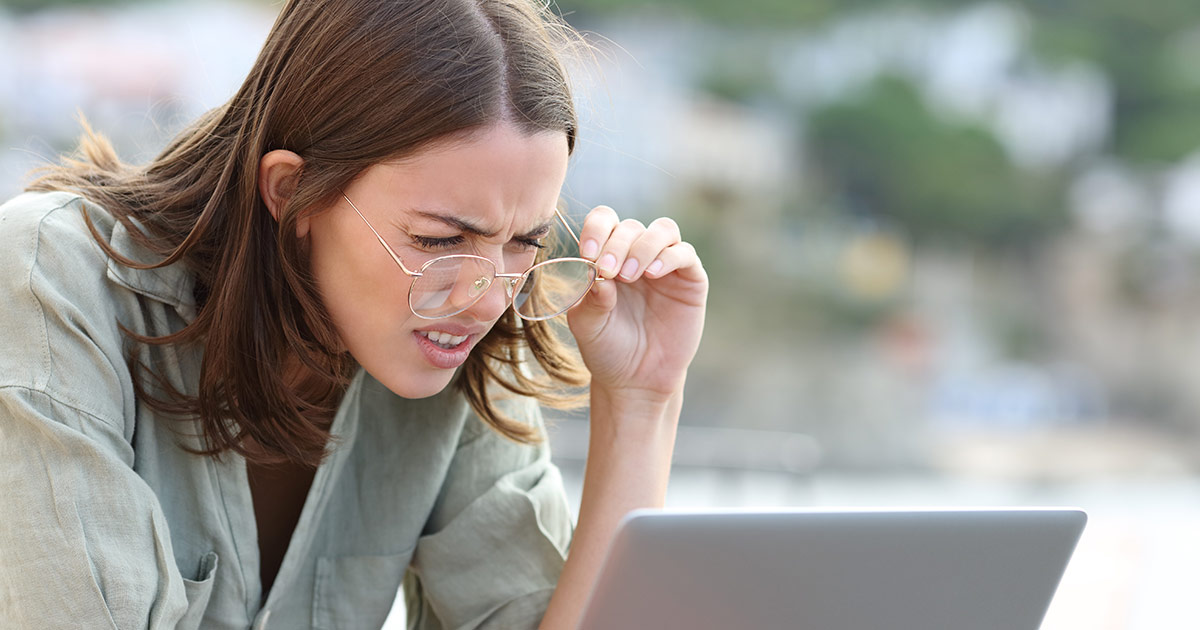 Frau versucht den Text von einem Laptop-Display zu lesen