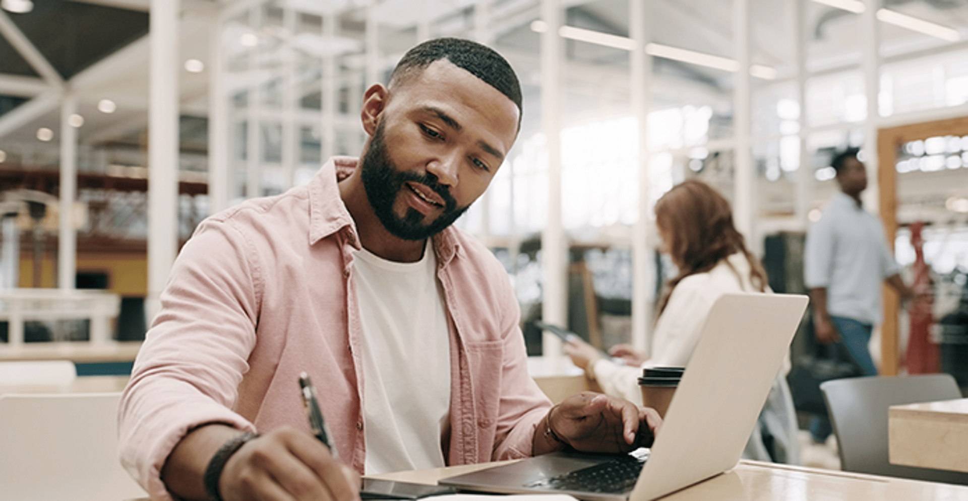 Man working at laptop making notes