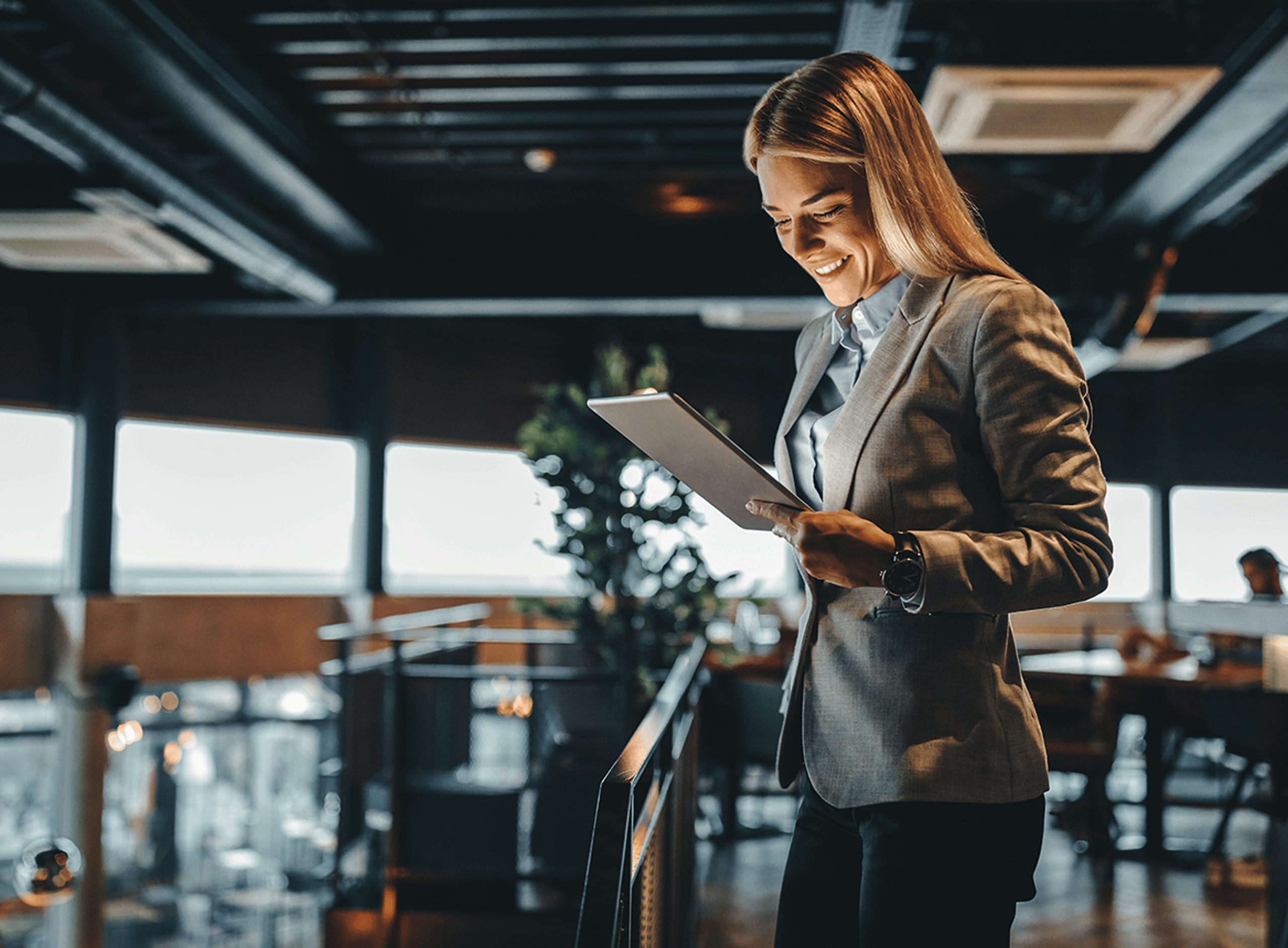 Blonde Woman Smiling and Looking at Tablet